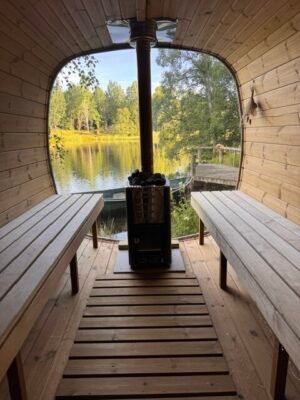 Innenansicht der mobilen Sauna TimberIN Nordic Square mit Holzbänken und Holzofen an einem See