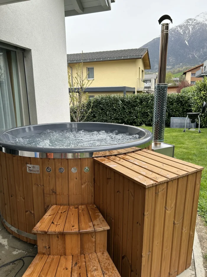 Badefass mit Holzverkleidung und Einstiegstreppe auf einer Terrasse