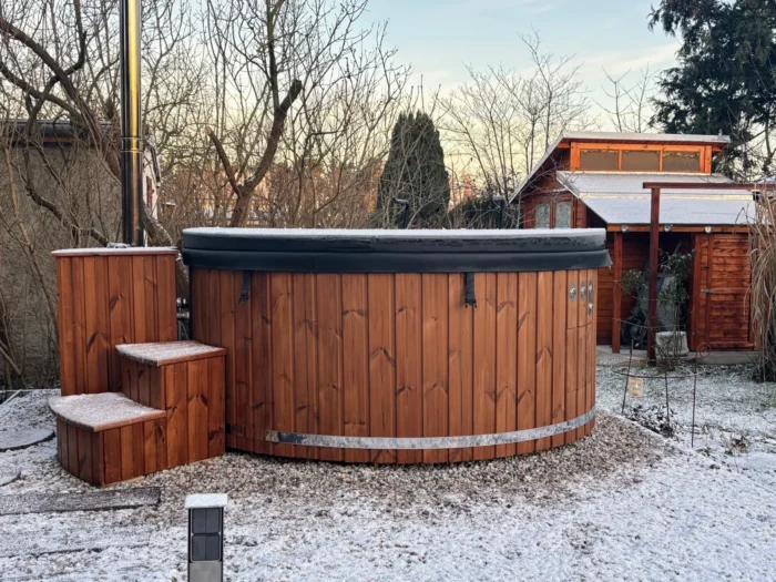 Abgedecktes Badefass mit Holzverkleidung im verschneiten Garten
