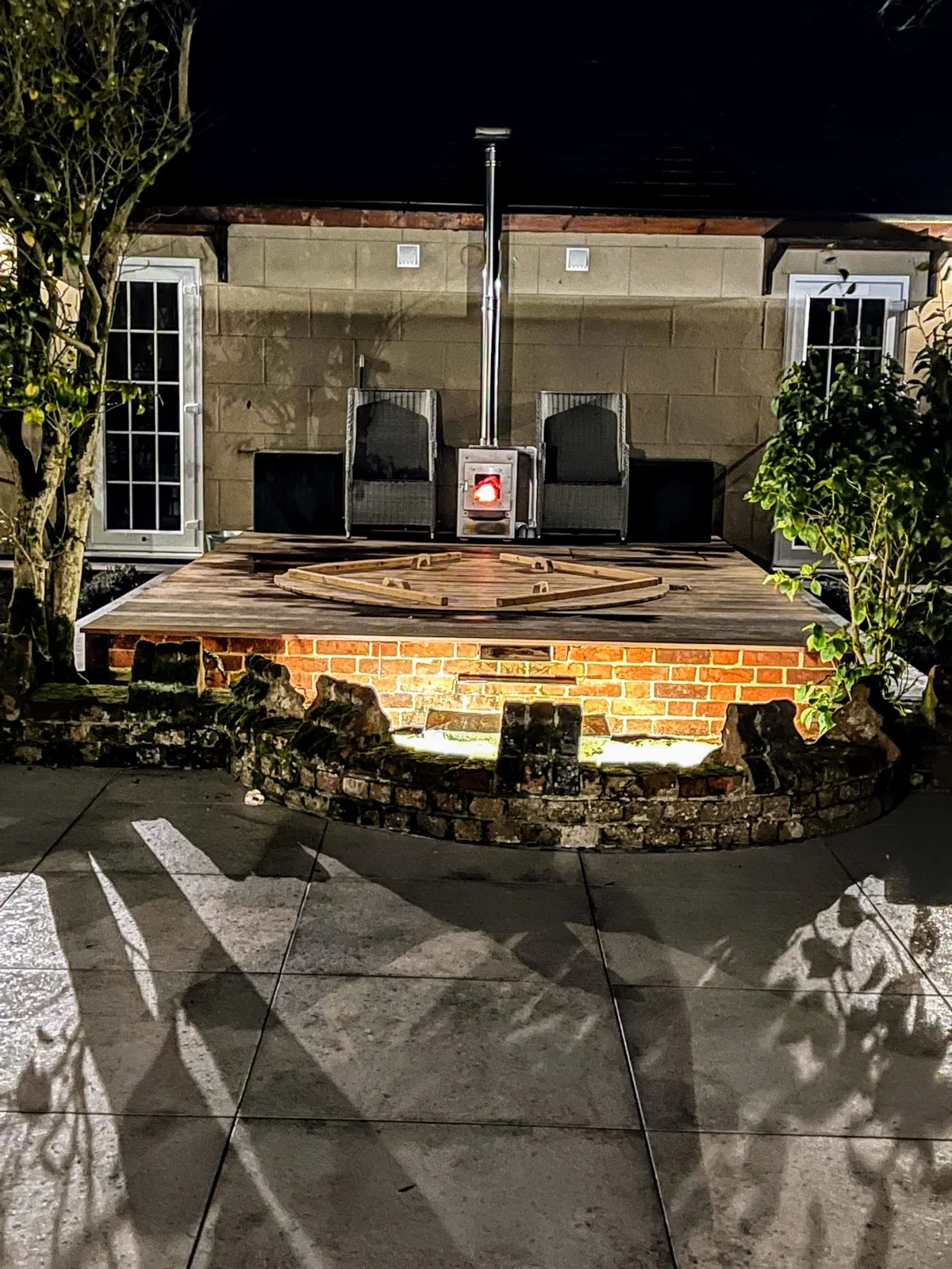 Badefass-Ofen raucht stark: Ursachen systematisch prüfen 1 In eine Terrasse eingelassenes Badefass mit Außenofen bei Nacht