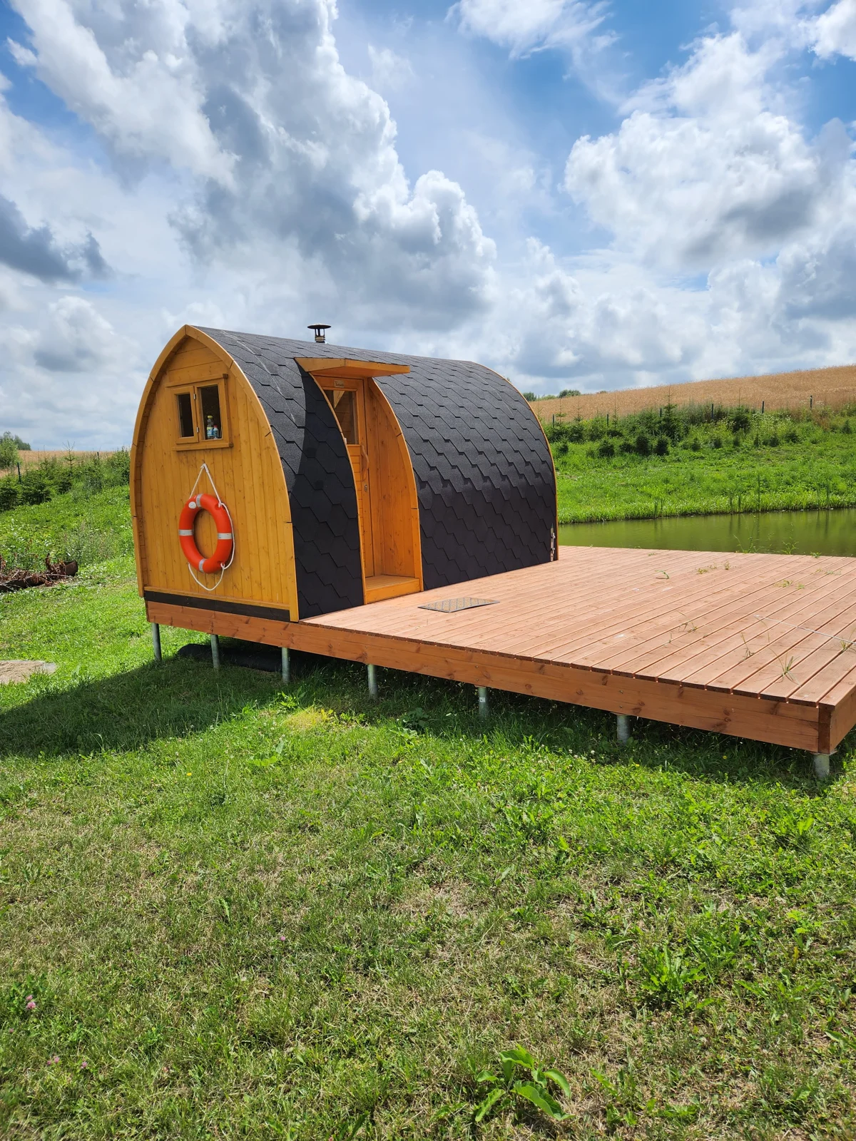 Außensauna mit vorgelagerter Holzterrasse an einer Wiese