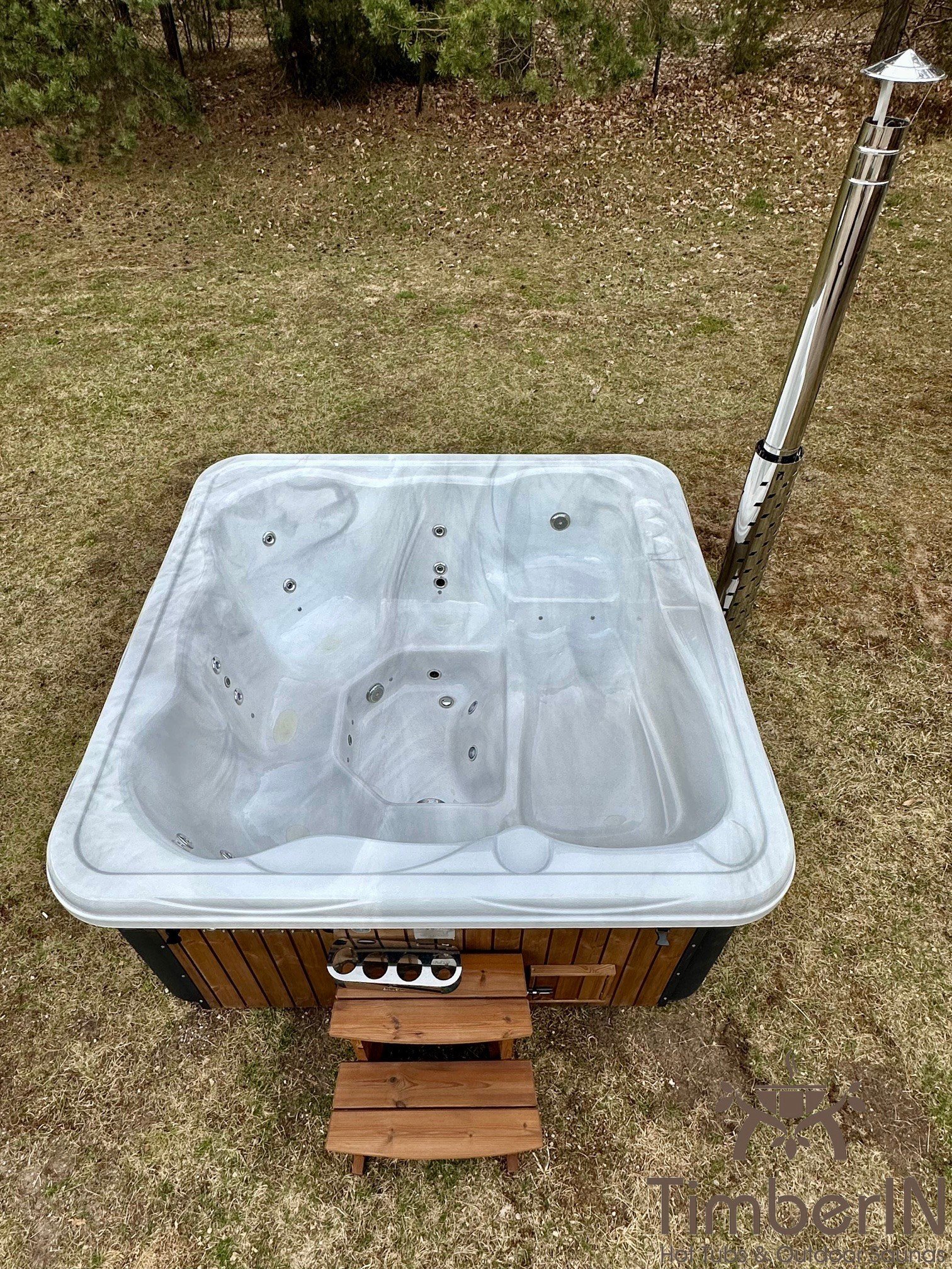 Acryl 1 Quadratisches Badefass mit weißer Acrylwanne und Holztreppe in einem angelegten Garten