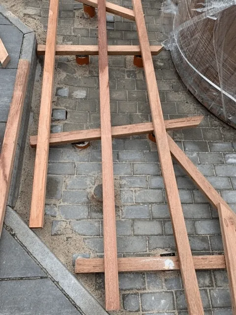 Untergrund 12 Offene Holzunterkonstruktion für einen schmalen Terrassensteg neben einem runden Badefass