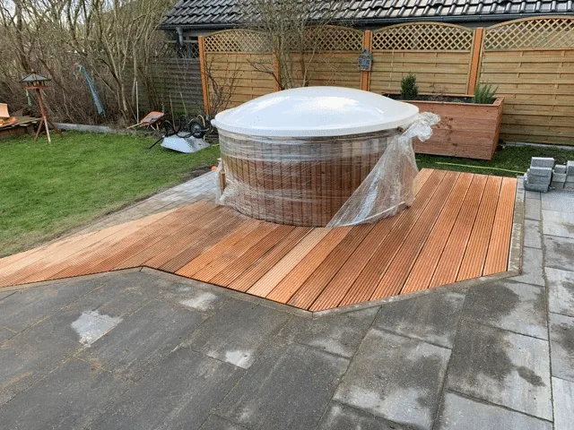 Untergrund 15 Abgedecktes rundes Badefass in einer gebogenen Holzterrasse mit freiem Pflasterweg und Gartenumgebung