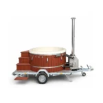 Lieferung 11 TimberIN Nordic Mobile™ – rundes holzbefeuertes Badefass mit rotbrauner Verkleidung, hellem Einsatz, Holztreppe, externem Edelstahl-Ofen und einachsigem Anhänger auf weißem Hintergrund.