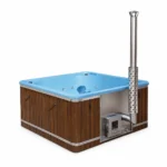 Rund 12 TimberIN Nordic Elite™ Square – großes quadratisches holzbefeuertes Badefass mit blauem Formeinsatz, Holz- und dunkler Paneelverkleidung, integriertem Ofen und hohem Edelstahlschornstein auf weißem Hintergrund.
