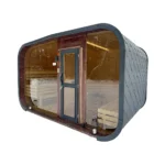 balkon 8 TimberIN Nordic Horizon™ – moderne Gartensauna-Kabine mit gerundetem dunklem Dach, Panorama-Glasfront, mittiger Tür und sichtbaren gestuften Holzbänken auf weißem Hintergrund.