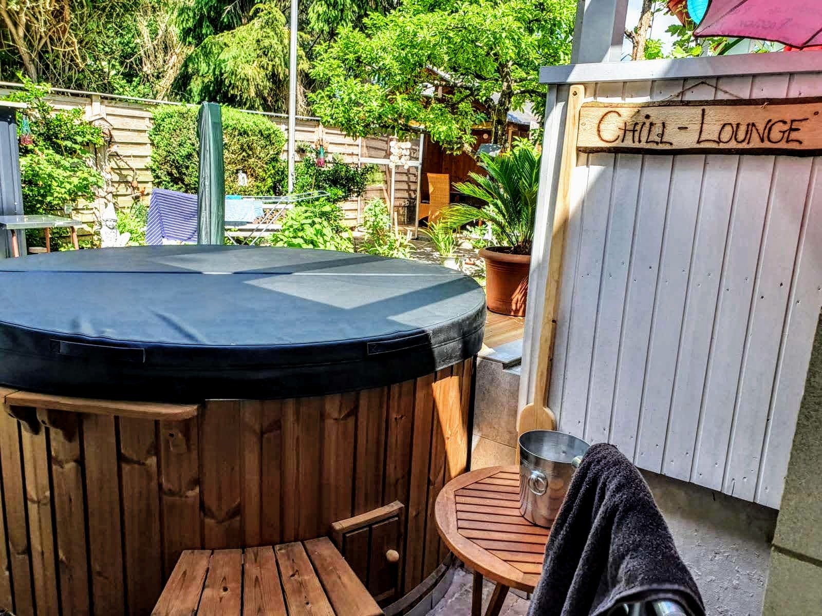 Abgedecktes Badefass auf einer Terrasse mit Gartenmöbeln