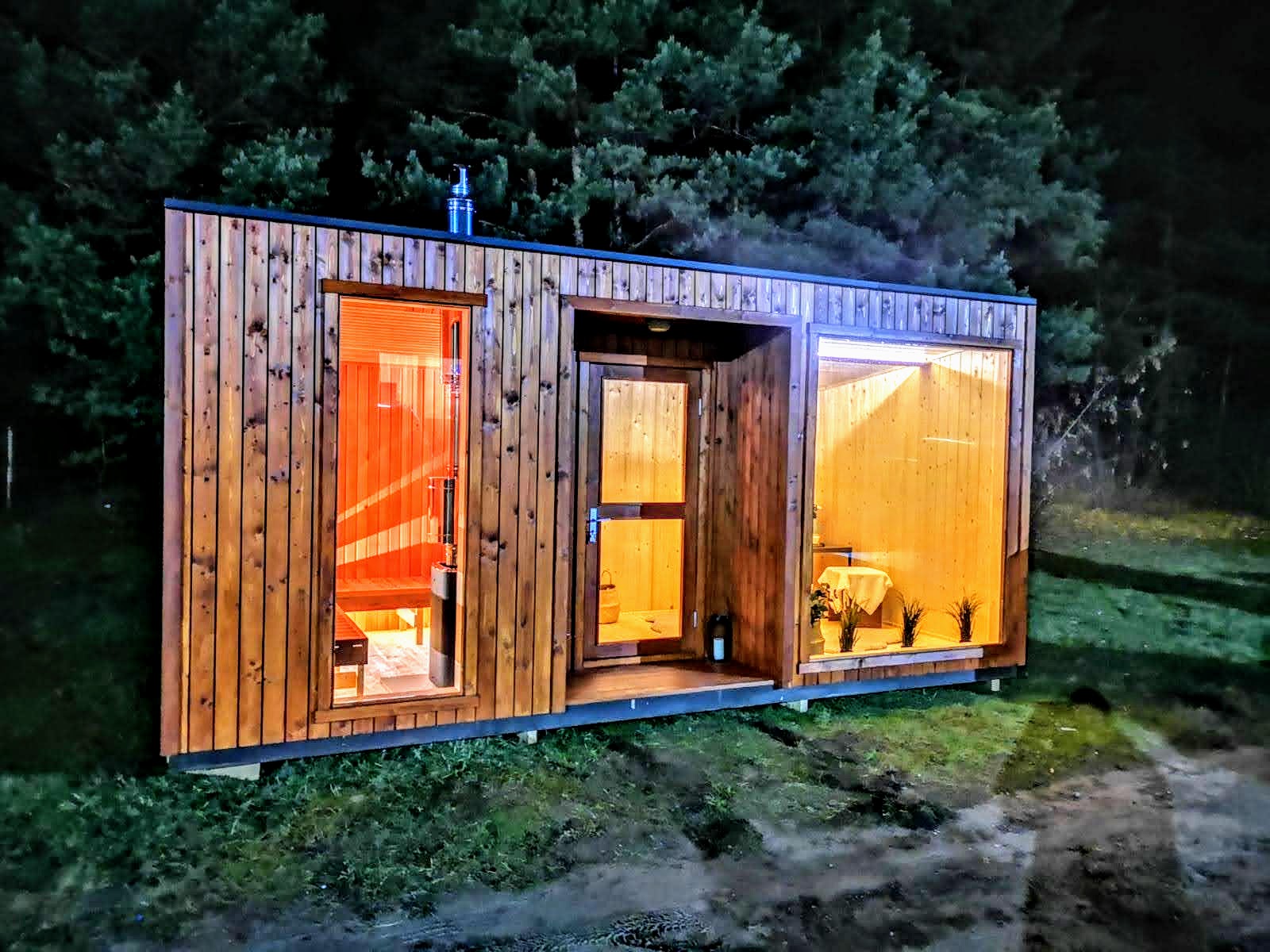 Modern 1 Moderne rechteckige Gartensauna aus Holz mit großen Glasflächen auf einer Wiese