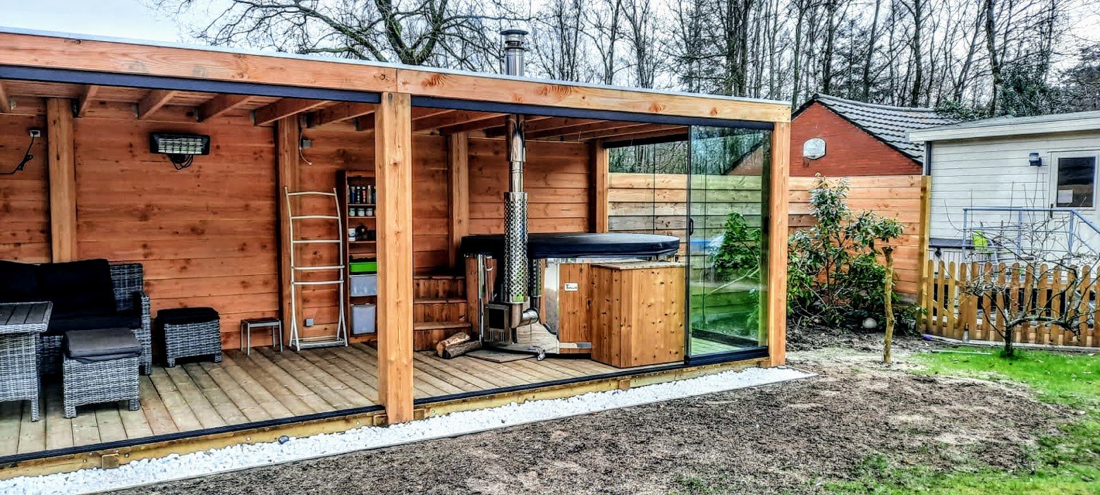 Badefass mit Holzofen unter einem Gartenpavillon