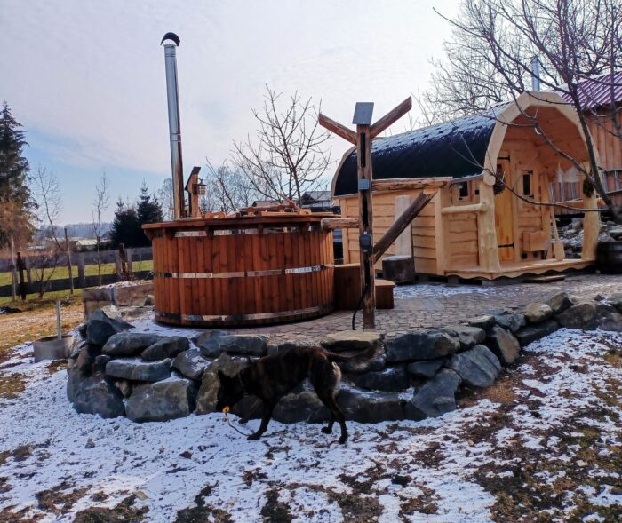 Österreich 1 Holzbadefass mit Abdeckung und Schornstein neben einer Sauna in verschneiter Umgebung