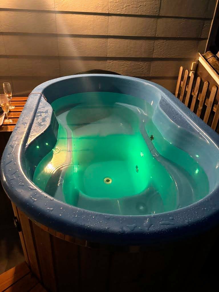 Ovales Badefass mit gegenüberliegenden Sitzen und grüner Unterwasserbeleuchtung