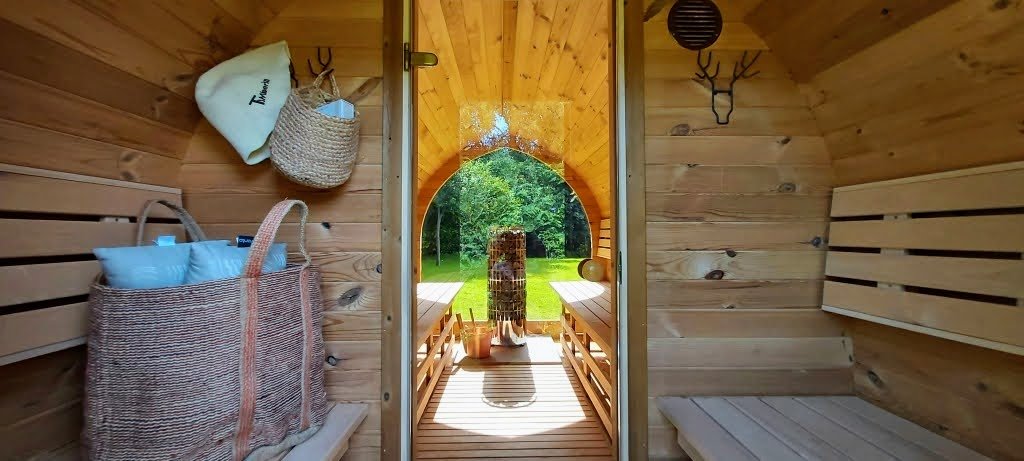 Mit Vorraum 1 Vorraum mit Holzbänken und Taschen; eine Glastür trennt ihn vom Saunaraum mit Ofen und Panoramafenster.