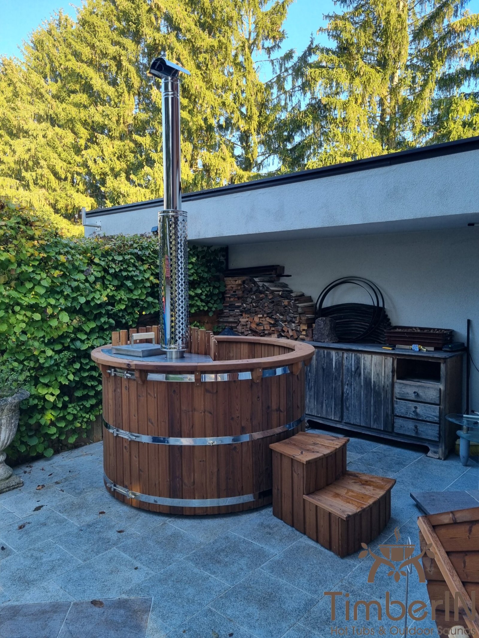 Holzarten für Badefässer 1 Rundes braunes Thermoholz-Badefass mit Treppe auf einer Terrasse